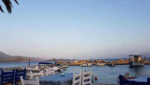 Un restaurante frente al mar con terraza, vistas al océano y barcos amarrados cerca.