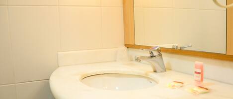 Un bagno con lavandino bianco, specchio e doccia.