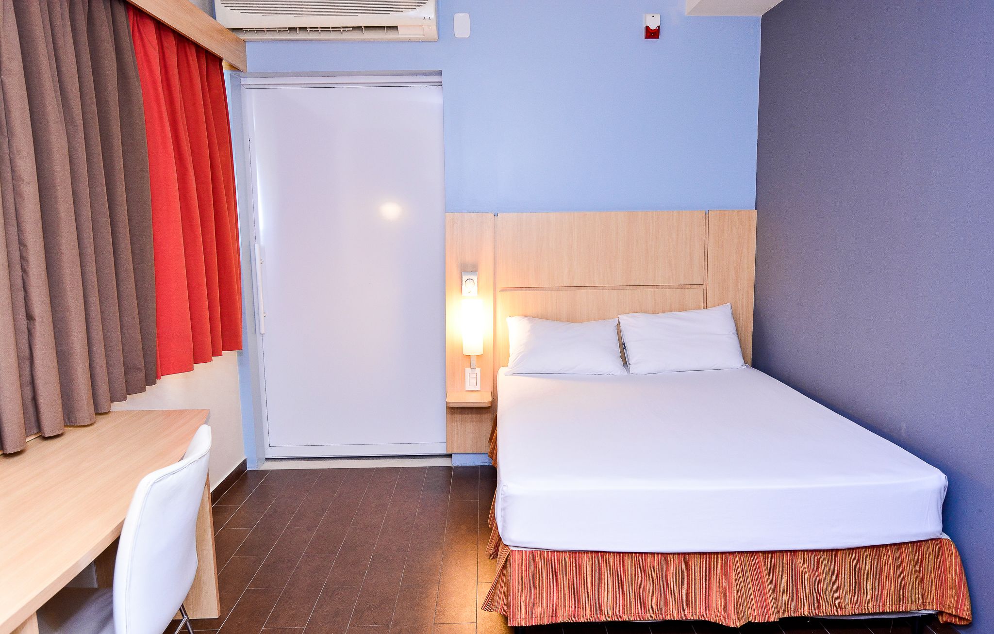 A hotel room with a bed, a desk, and a chair.