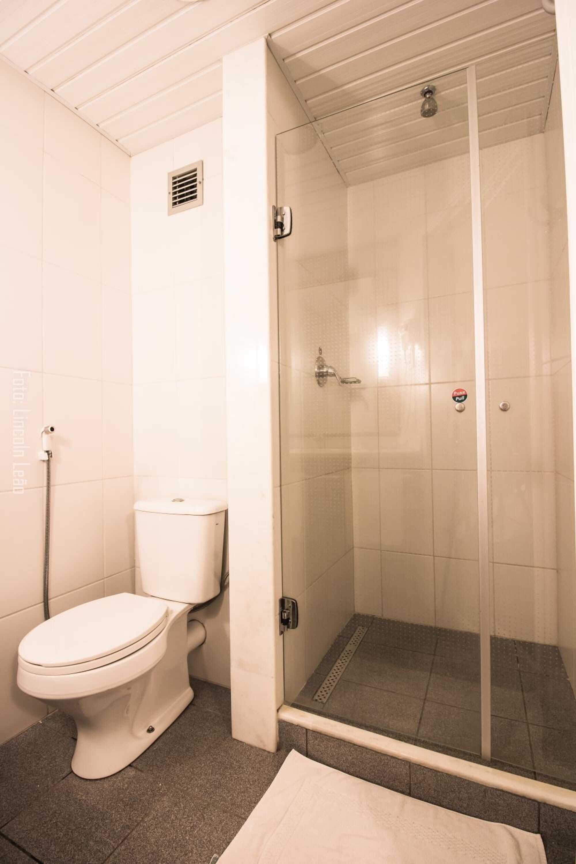 A bathroom with a toilet, a shower enclosure, and a towel rack.
