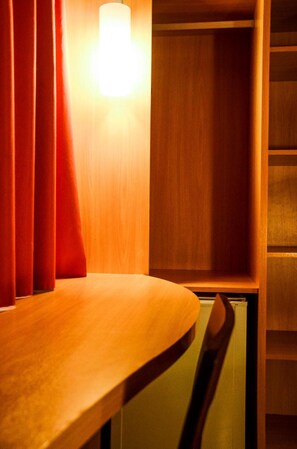 A wooden chair and a wooden table with a red curtain partially drawn.
