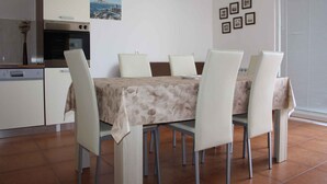 A dining area with a table set for four, surrounded by chairs, in a modern kitchen with a built-in oven and a dishwasher.