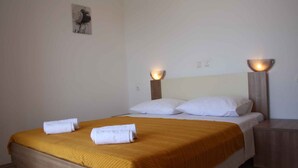 A neatly made bed with a yellow bedspread, white pillows, and two bedside lamps.
