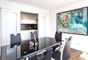 Ein zeitgemäßer Essbereich mit einem Glastisch, schwarzen Stühlen und einem Gemälde an der Wand.