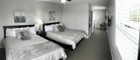 A hotel room with two beds, a ceiling fan, and artwork on the walls.