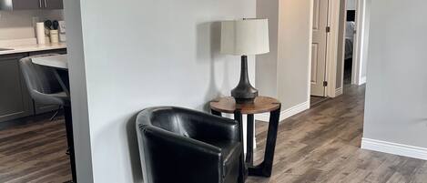 A modern interior with a dining area, a black leather chair, a wooden table, and a lamp.