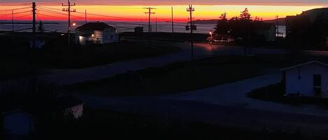 A residential area with houses, a road, and power lines during sunset.