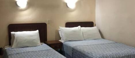 Una habitación de hotel con dos camas individuales, un ventilador de techo e iluminación en la pared.