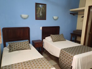 Une chambre d’hôtel avec deux lits, une table de chevet, un tableau accroché au mur et une petite table avec une chaise.