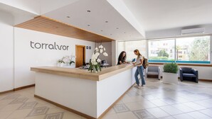 A reception desk with a sign reading "torralvor" in a modern hotel lobby with patterned tiles and large windows. - Dunas do Alvor - Torralvor (Portimão)
