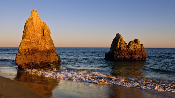 A beach with large rock formations and calm waves. - Dunas do Alvor - Torralvor (Portimão)