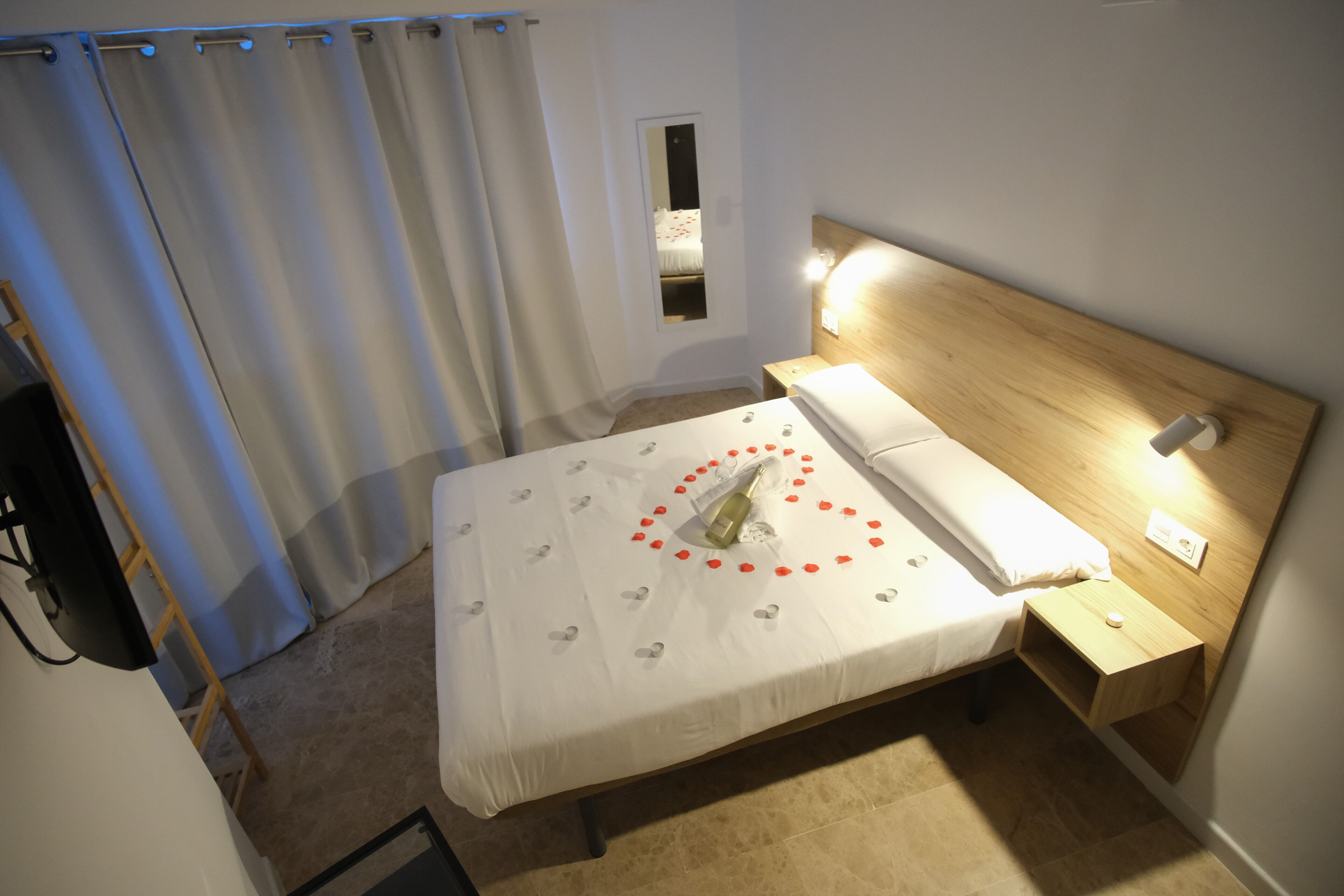 A neatly made bed with a white bedspread, a wooden headboard, and a bedside table with a lamp.