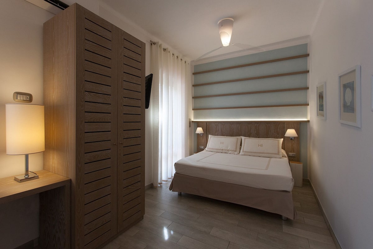 Ein Hotelzimmer mit Bett, Nachttischlampen, einem Holzschrank und einem Deckenventilator.