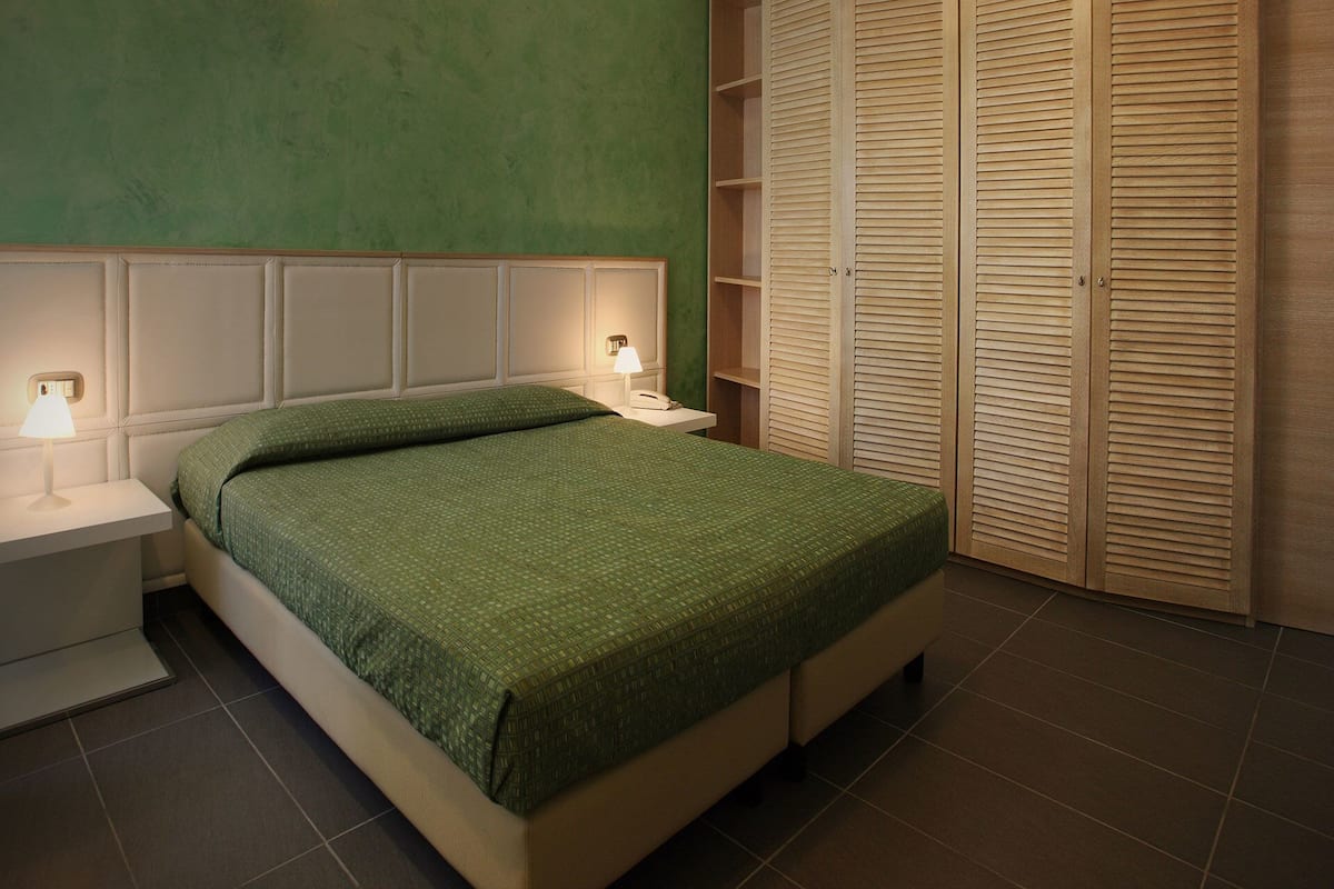 Ein ordentlich eingerichtetes Schlafzimmer mit einem Bett, Nachttischlampen und einem Kleiderschrank.