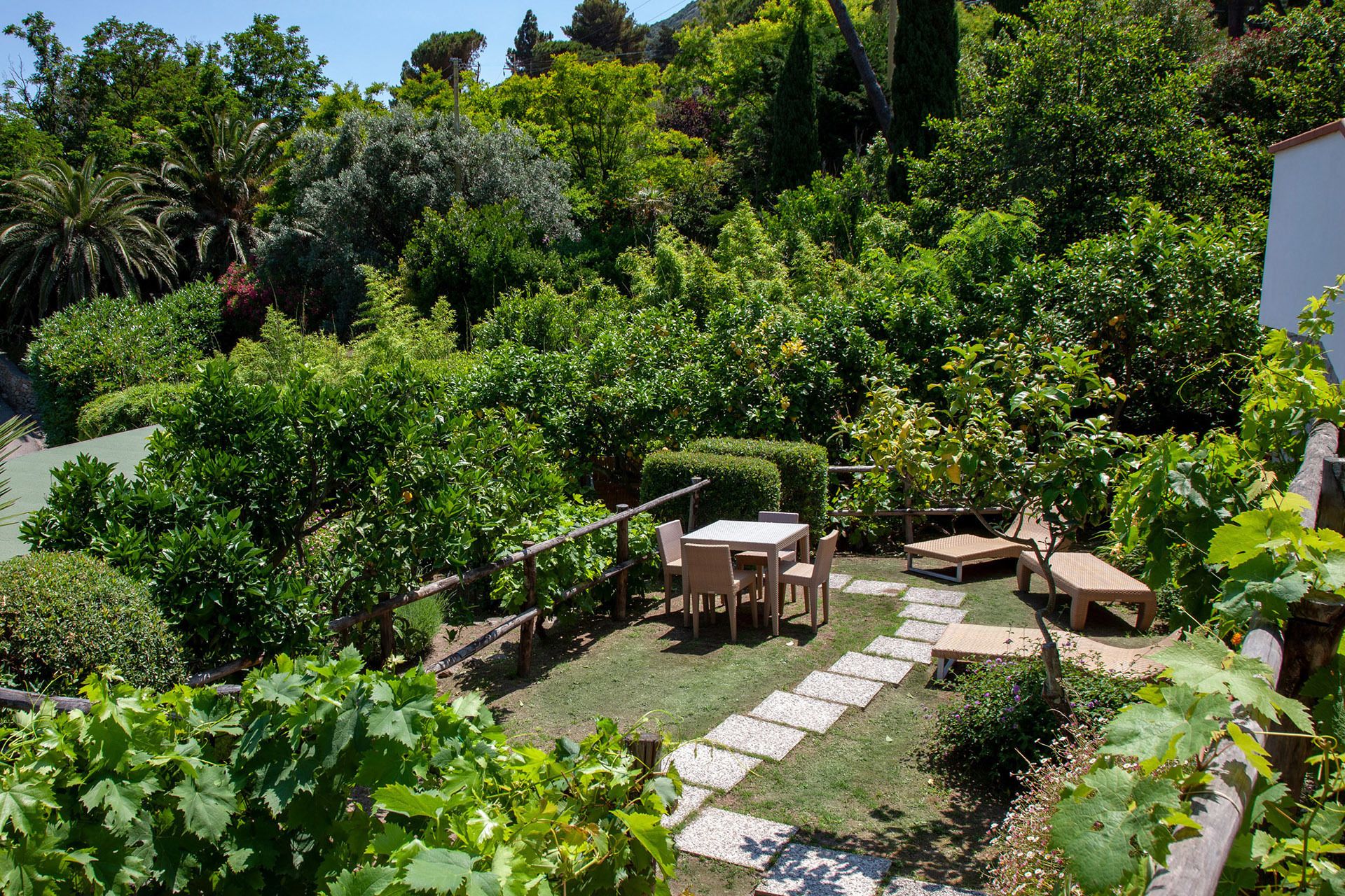 A garden with a table and chairs, a stone pathway, and various plants.