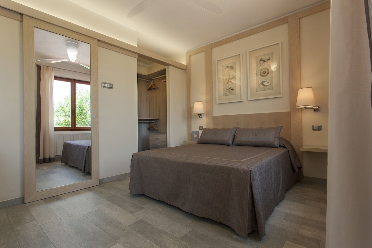 Ein Schlafzimmer mit einem großen Bett, einem Spiegel und zwei Wandleuchten.