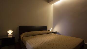 Una camera da letto con un letto, due comodini e una lampada a parete.