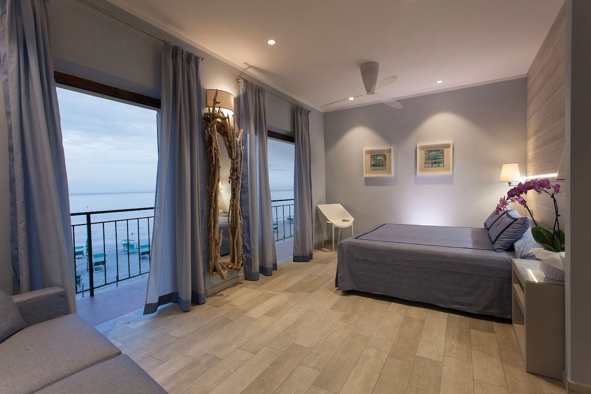 Ein modernes Schlafzimmer mit großem Fenster, einem Bett, einem Schreibtisch und einem Stuhl.
