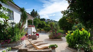 Une terrasse aménagée avec du mobilier d’extérieur, un chemin en pierre et diverses plantes.