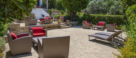 An outdoor patio with wicker furniture, a stone wall, and a view of a mountain.