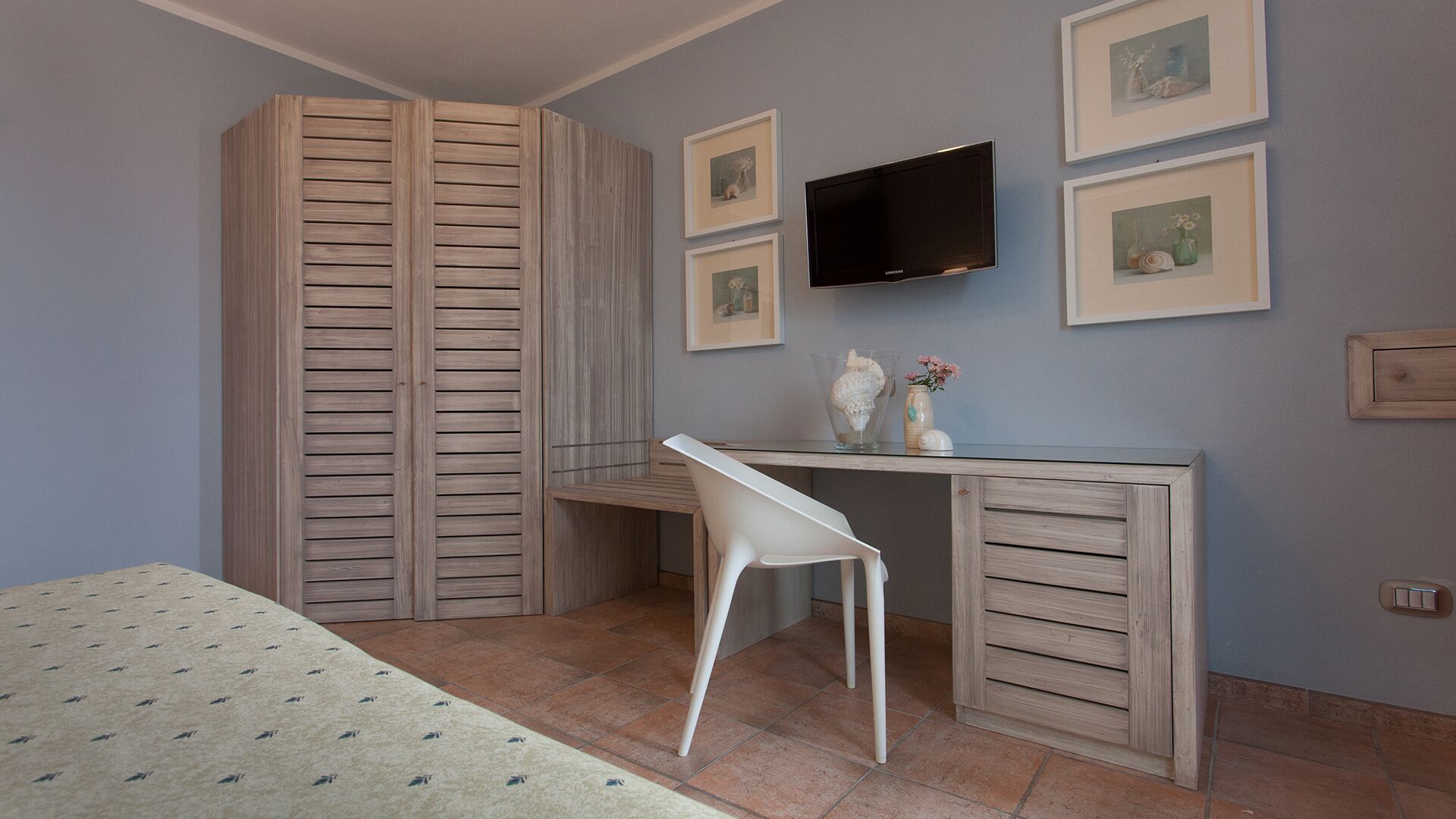 A bedroom with a bed, a desk, a chair, a TV, and a wardrobe.