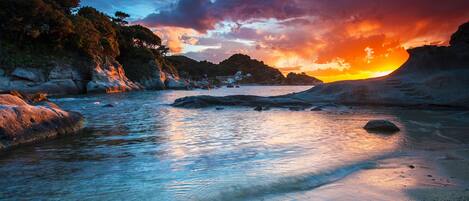 Un paisaje costero con mar tranquilo, costas rocosas y un atardecer.