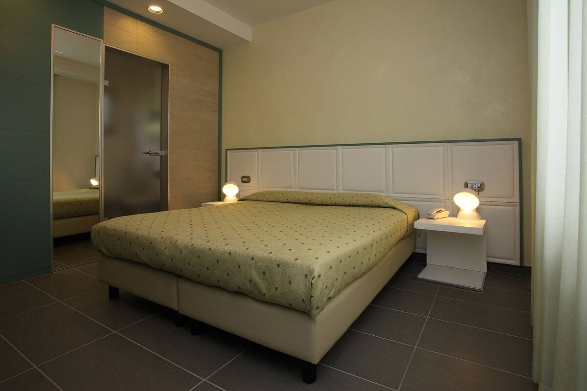 Ein ordentlich eingerichtetes Schlafzimmer mit einem Bett, Nachttischen und einem Spiegel.
