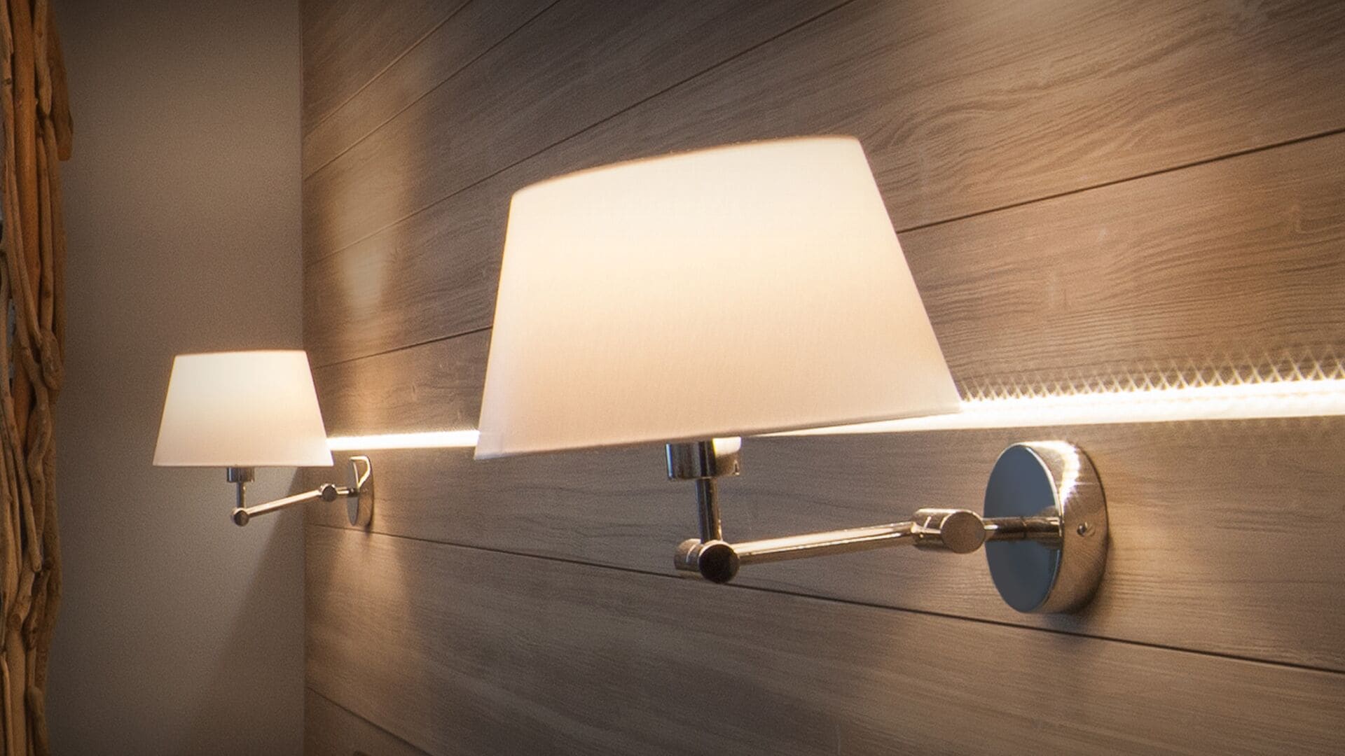 Two wall-mounted lamps with white shades against a wooden wall.