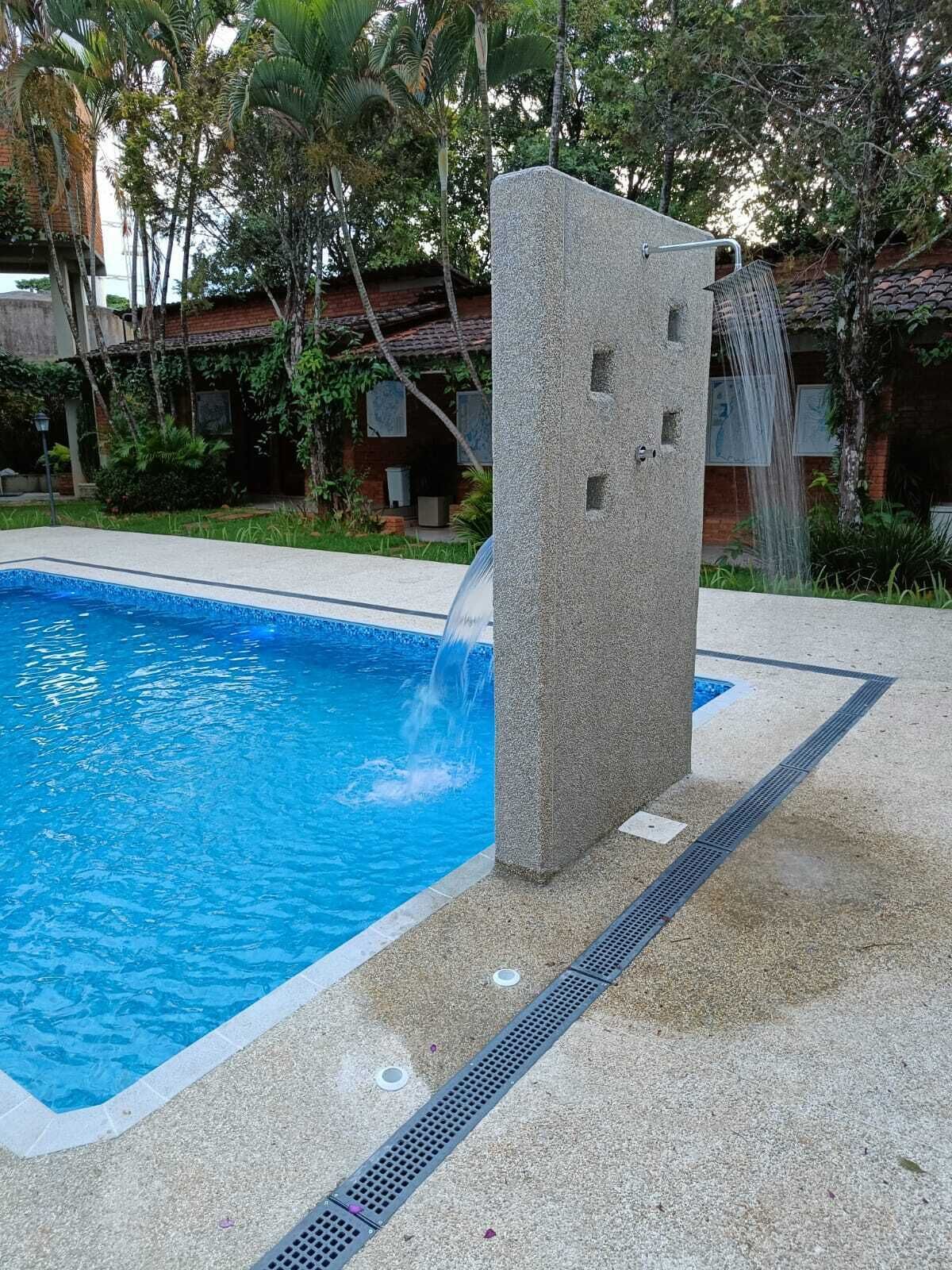 A swimming pool with a waterfall feature and a stone structure.