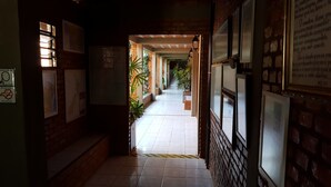A corridor with tiled flooring, brick walls, and framed pictures. - Pousada Barcelos (São Roque de Minas)