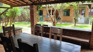 An outdoor patio with a wooden table and benches, surrounded by brick walls and greenery. - Pousada Barcelos (São Roque de Minas)