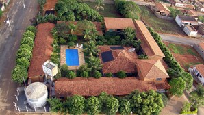 An aerial view of a residential area with a house featuring a swimming pool, a satellite dish, and a large water tank. - Pousada Barcelos (São Roque de Minas)
