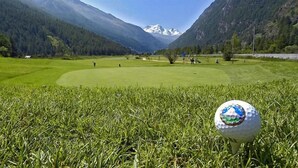 A golf course with a golf ball in the foreground and mountains in the background. - City Hotel Haupthaus and Nebenhaus (Taesch)