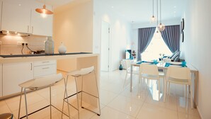 A modern kitchen with white cabinets, a bar stool, and pendant lighting.