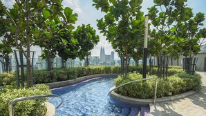 A swimming pool with a view of a city skyline, surrounded by trees and greenery.