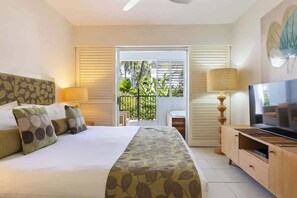 Una camera d'albergo con un letto, una televisione, un balcone con vista sul verde e una porta scorrevole.