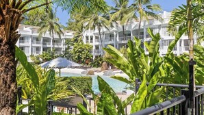 Ein Resort mit Pool, Palmen und einem weißen Gebäude mit Balkonen.