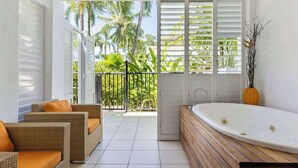 Ein Balkon mit Blick auf Palmen, einer weißen Badewanne und Korbmöbeln.
