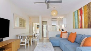 Ein modernes Wohnzimmer mit Sofa, Couchtisch, Fernseher und Essbereich.