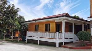 Une maison à deux étages avec une façade en bois, un toit recouvert de tuiles rouges et un balcon blanc.