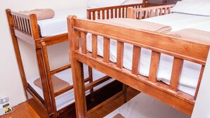 Un lit superposé avec une structure en bois et du linge de lit blanc.