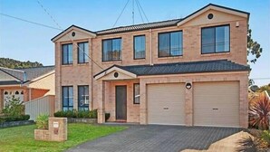A two-story house with a garage, a driveway, and a well-maintained lawn. - IDEAL FAMILY BEACH GETAWAY, 1 HR FROM SYDNEY!!! (Umina Beach)