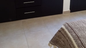 Una habitación con un armario negro, un tapete estampado y una ventana.