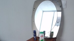 Un dormitorio con una mesita de noche de madera, un espejo y una cama con colcha estampada.
