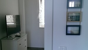 Una habitación con una televisión sobre un tocador, una ventana y cuadros colgados en la pared.