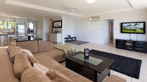 A modern living room with a large sofa, a coffee table, and a television. - Blue water Views 15, Beautiful Apartment on Hamilton Island (Hamilton Island)
