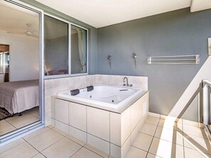 Une salle de bain moderne avec une grande baignoire, une douche et une porte en verre donnant sur un balcon.