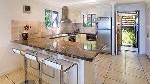 A modern kitchen with a large island, stainless steel appliances, and a view to a garden. - Blue water Views 15, Beautiful Apartment on Hamilton Island (Hamilton Island)