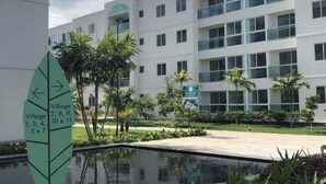 A modern building with multiple windows and a sign indicating directions to various village sections.