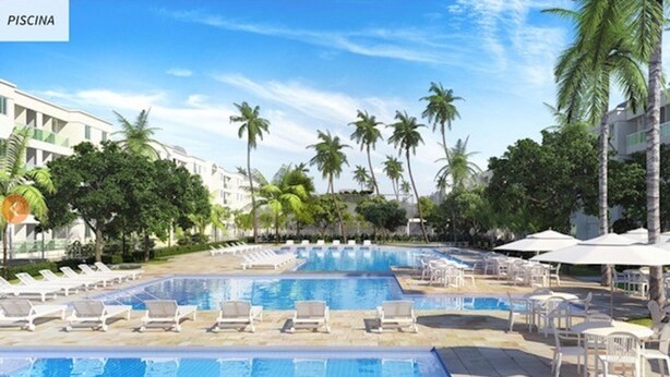 A swimming pool area with multiple pools, lounge chairs, and palm trees.